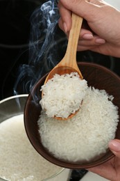 Woman taking boiled rice into bowl, closeup