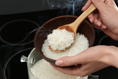 Photo of Woman taking boiled rice into bowl, closeup