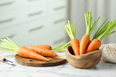 Tasty ripe juicy carrots in bowl on white marble table