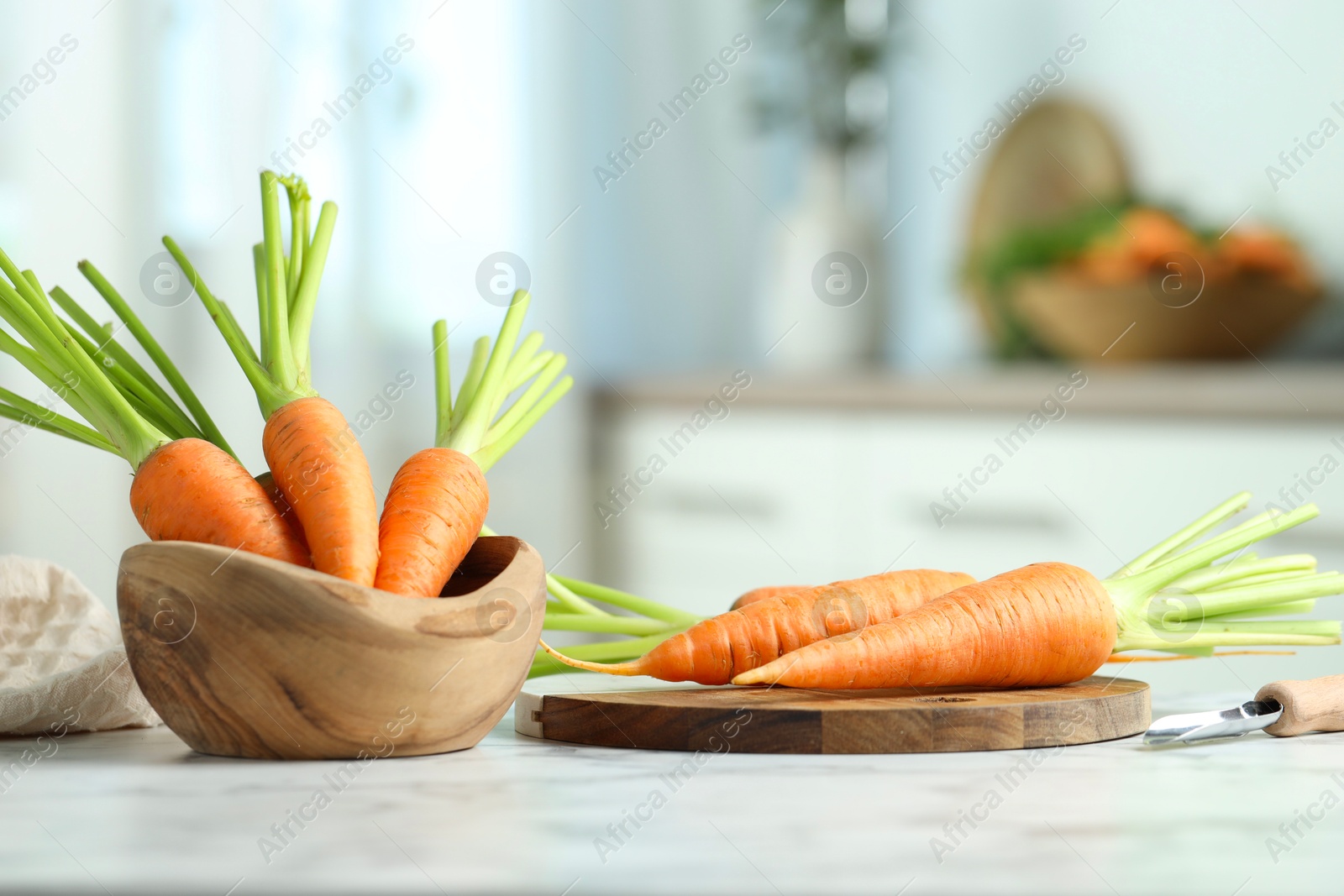 Photo of Tasty ripe juicy carrots in bowl on white marble table