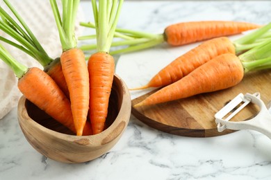 Photo of Tasty ripe juicy carrots in bowl on white marble table, closeup