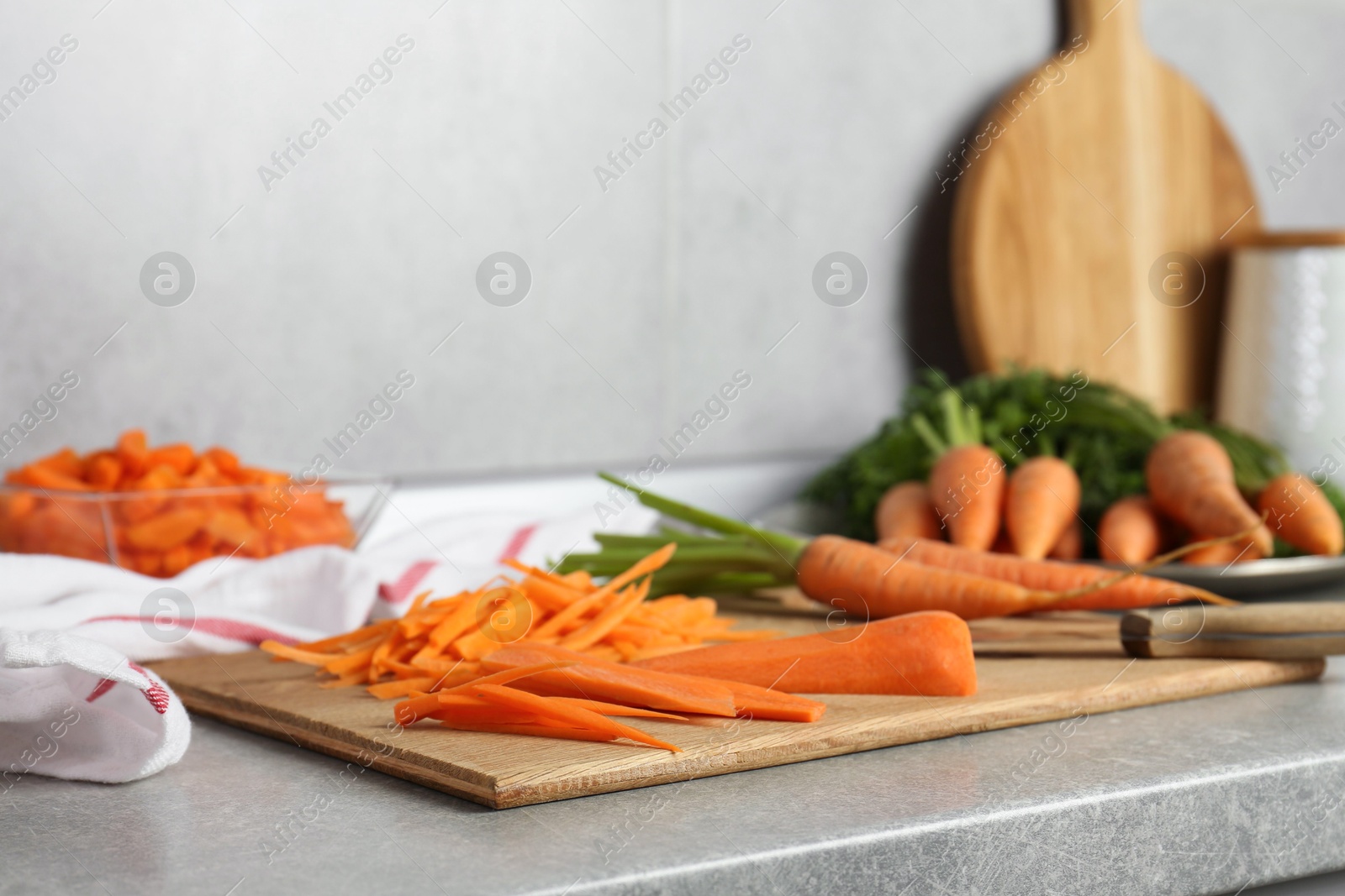 Photo of Pieces of fresh carrots on gray textured countertop, closeup