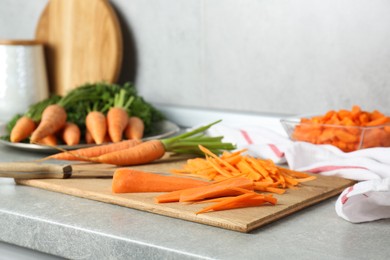 Photo of Pieces of fresh carrots on gray textured countertop, closeup