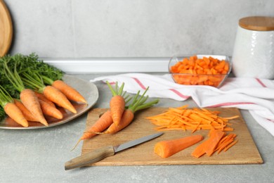 Photo of Fresh carrots and knife on gray textured table in kitchen