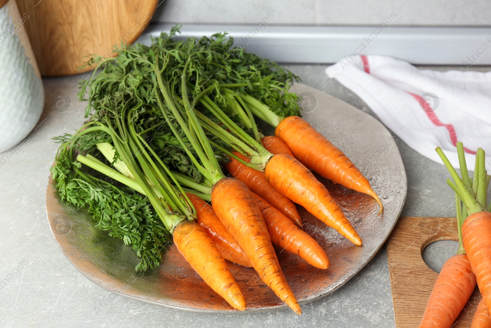 Photo of Tasty ripe juicy carrots on gray textured table, closeup