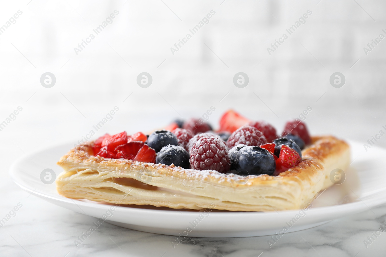 Photo of Tasty puff pastry with berries on white marble table, closeup