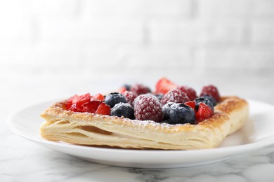 Photo of Tasty puff pastry with berries on white marble table, closeup