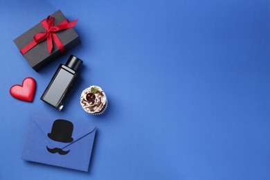 Photo of Happy Father's Day. Creative envelope, bottle of perfume, gift, decorative heart and cupcake on blue background, flat lay. Space for text