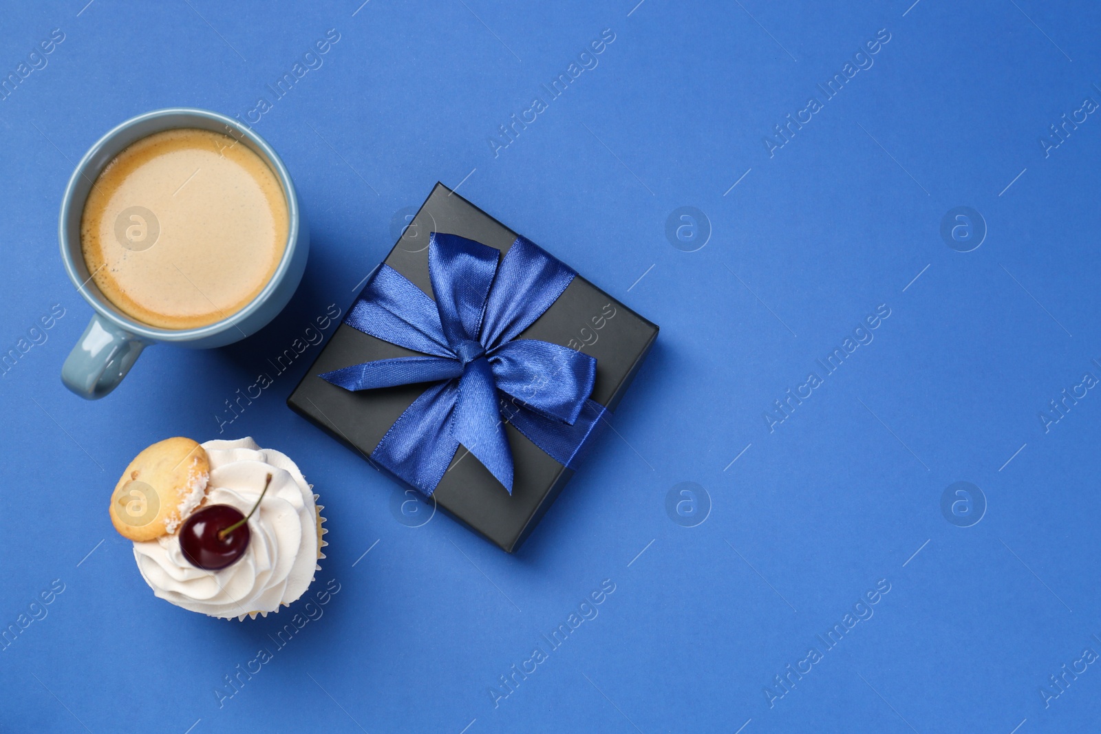 Photo of Happy Father's Day. Gift box, cupcake and cup with coffee on blue background, flat lay. Space for text