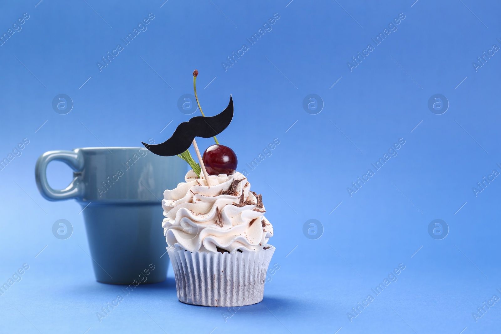 Photo of Happy Father's Day. Cupcake with mustache topper and cup on blue background. Space for text