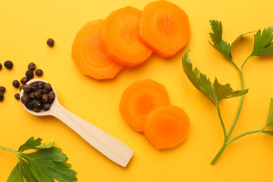 Photo of Slices of fresh ripe carrot, spices and spoon on yellow background, flat lay