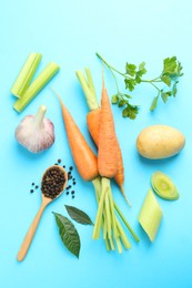 Fresh ripe carrots, vegetables, spices and spoon on light blue background, flat lay