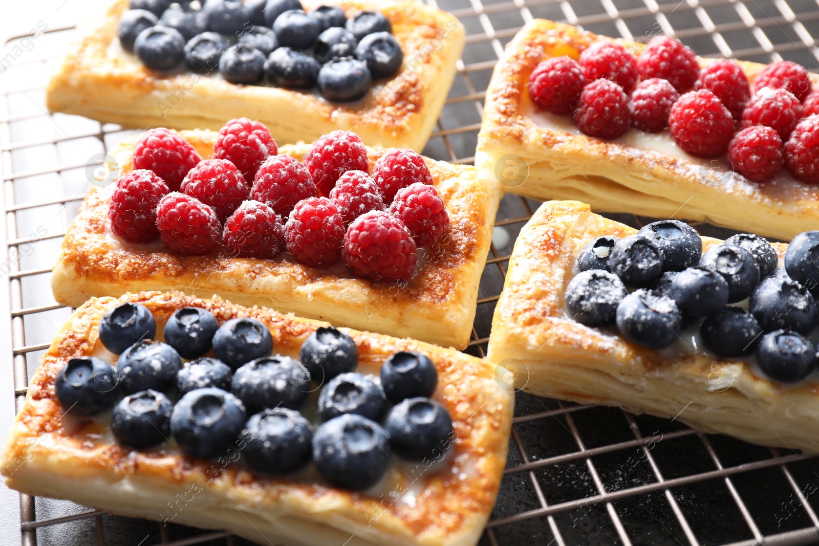 Photo of Tasty puff pastries with berries on grey table, closeup