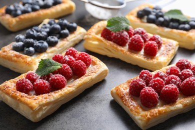 Photo of Tasty puff pastries with berries on grey table, closeup