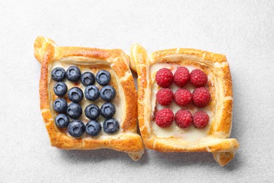 Tasty puff pastries with berries on white table, top view