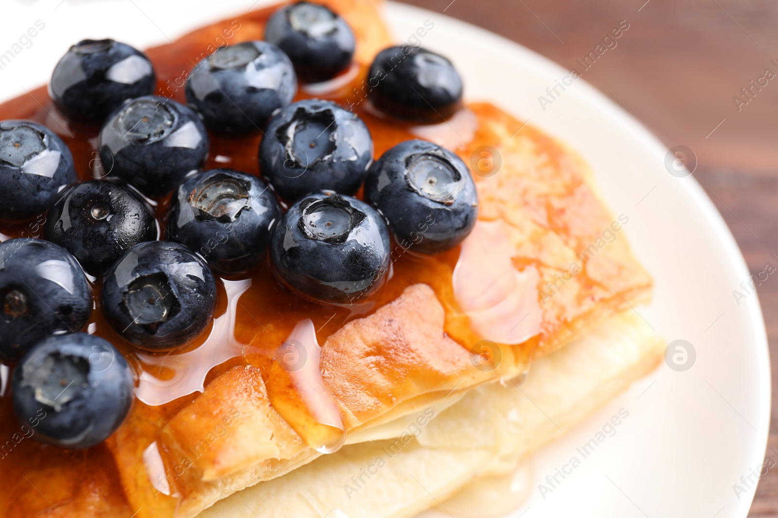 Photo of Tasty puff pastry with blueberries on wooden table, closeup