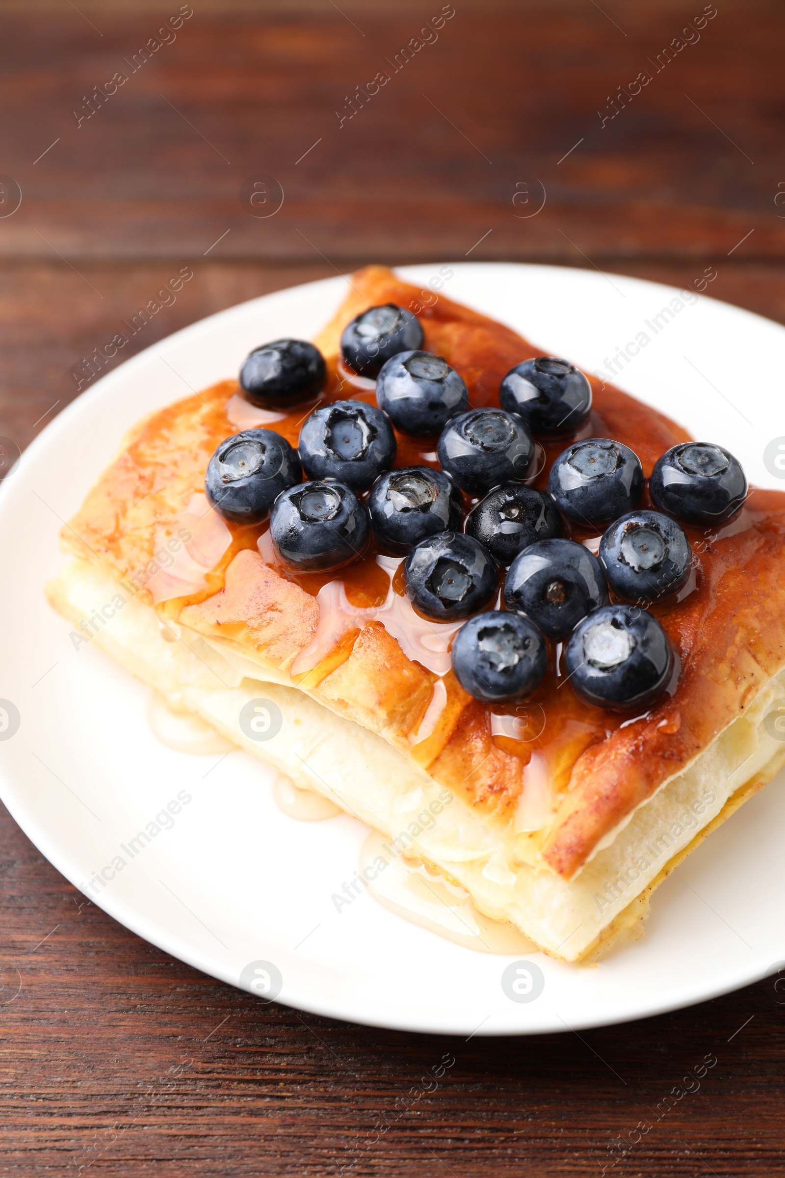 Photo of Tasty puff pastry with blueberries on wooden table, closeup