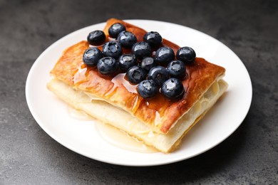 Tasty puff pastry with blueberries on grey table, closeup