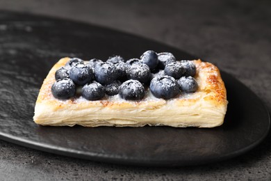 Tasty puff pastry with blueberries on grey table, closeup