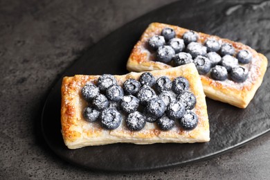 Photo of Tasty puff pastries with blueberries on grey table, closeup