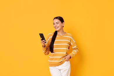 Photo of Smiling woman with smartphone on yellow background