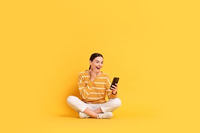 Photo of Happy woman with smartphone on yellow background