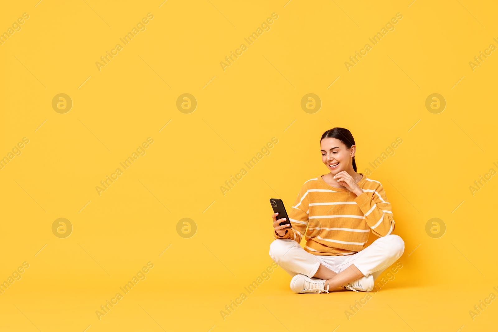 Photo of Happy woman with smartphone on yellow background. Space for text