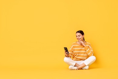 Photo of Happy woman with smartphone on yellow background. Space for text