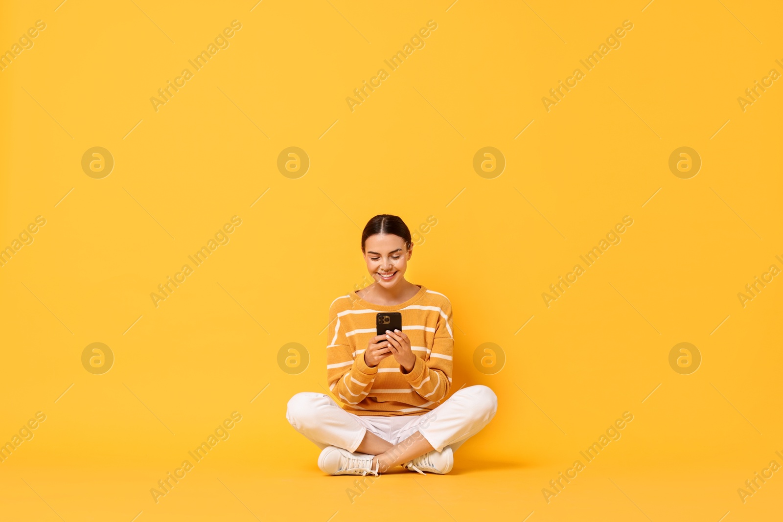 Photo of Happy woman with smartphone on yellow background. Space for text