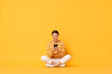 Photo of Happy woman with smartphone on yellow background. Space for text