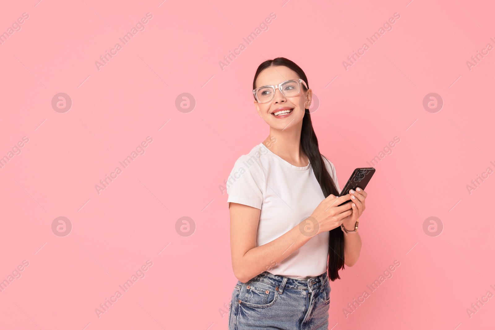 Photo of Smiling woman with smartphone on pink background. Space for text