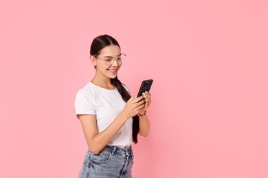 Photo of Smiling woman with smartphone on pink background. Space for text