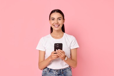 Smiling woman with smartphone on pink background