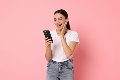 Photo of Happy woman with smartphone on pink background