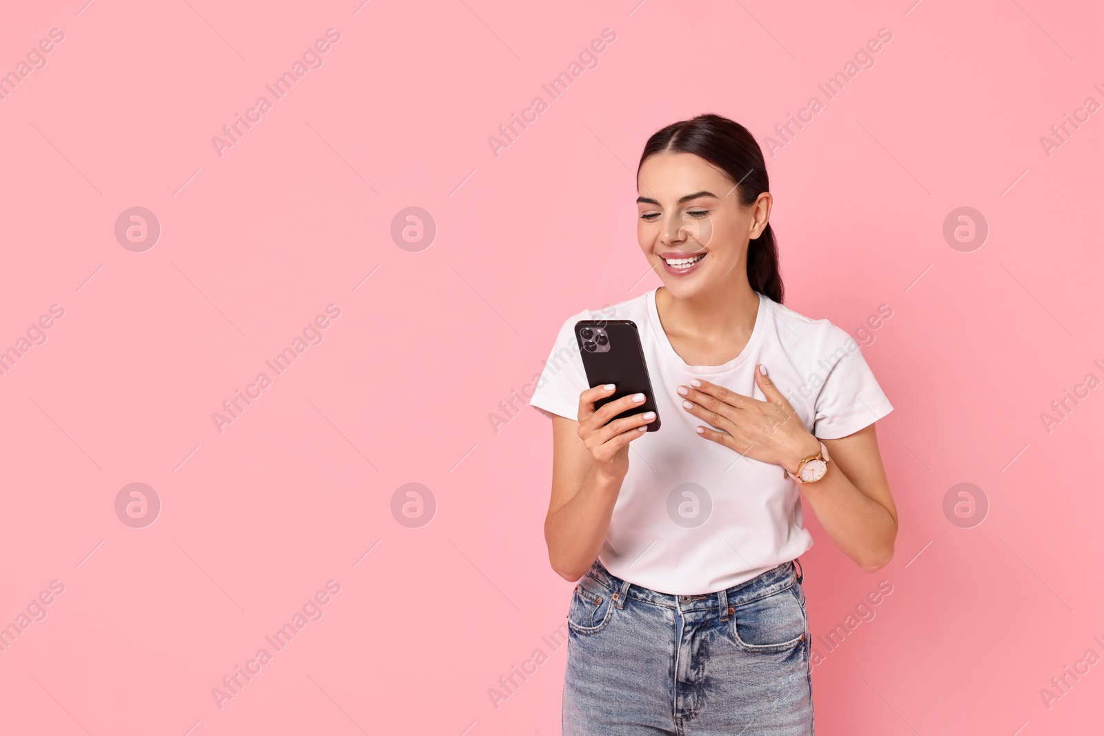 Photo of Smiling woman with smartphone on pink background. Space for text