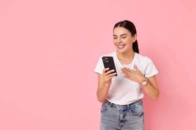 Photo of Smiling woman with smartphone on pink background. Space for text