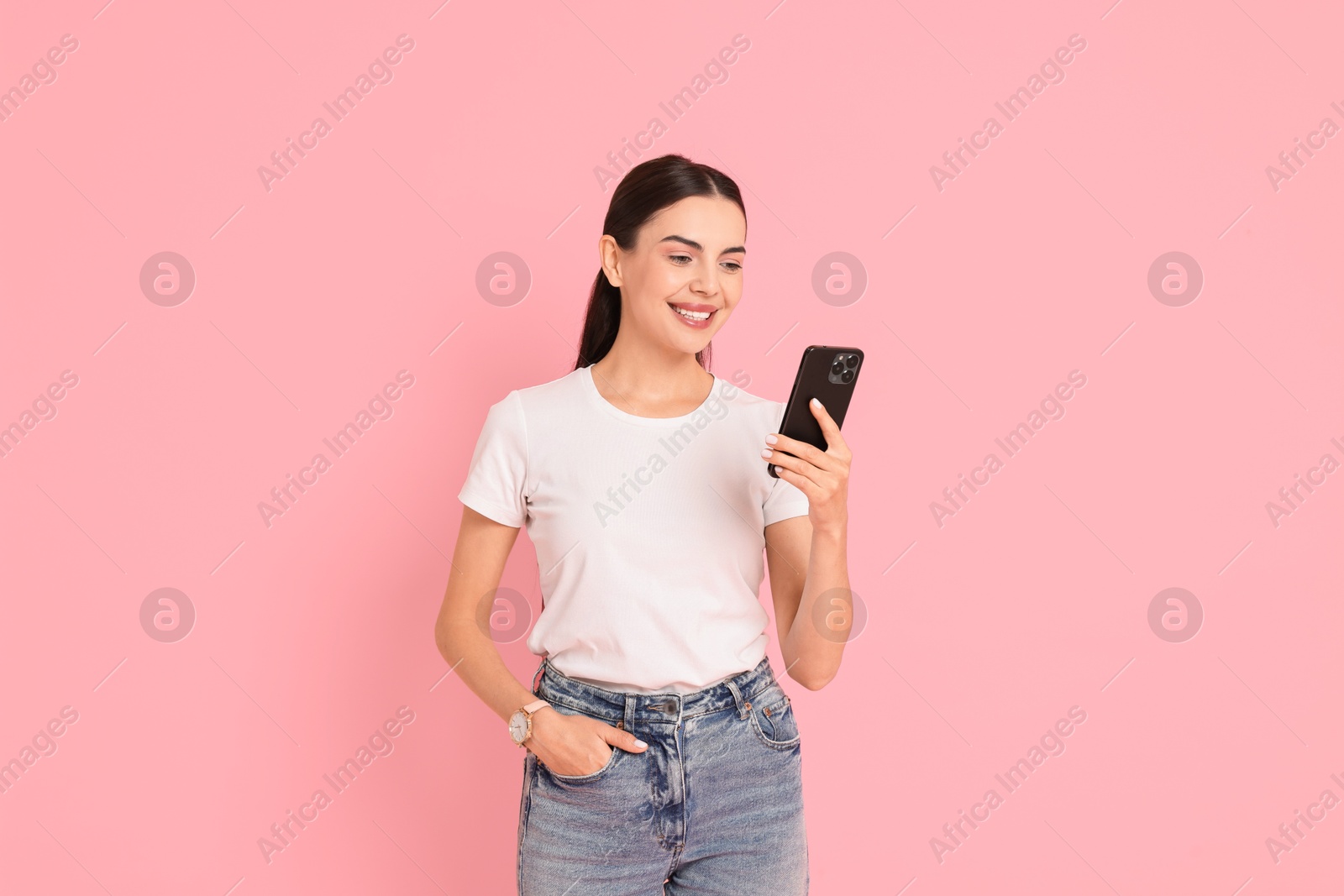 Photo of Smiling woman with smartphone on pink background