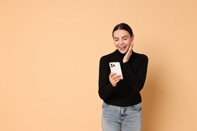 Photo of Smiling woman with smartphone on beige background. Space for text