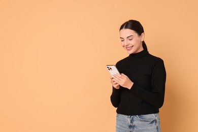 Smiling woman with smartphone on beige background. Space for text