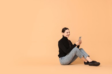 Photo of Smiling woman with smartphone on beige background. Space for text