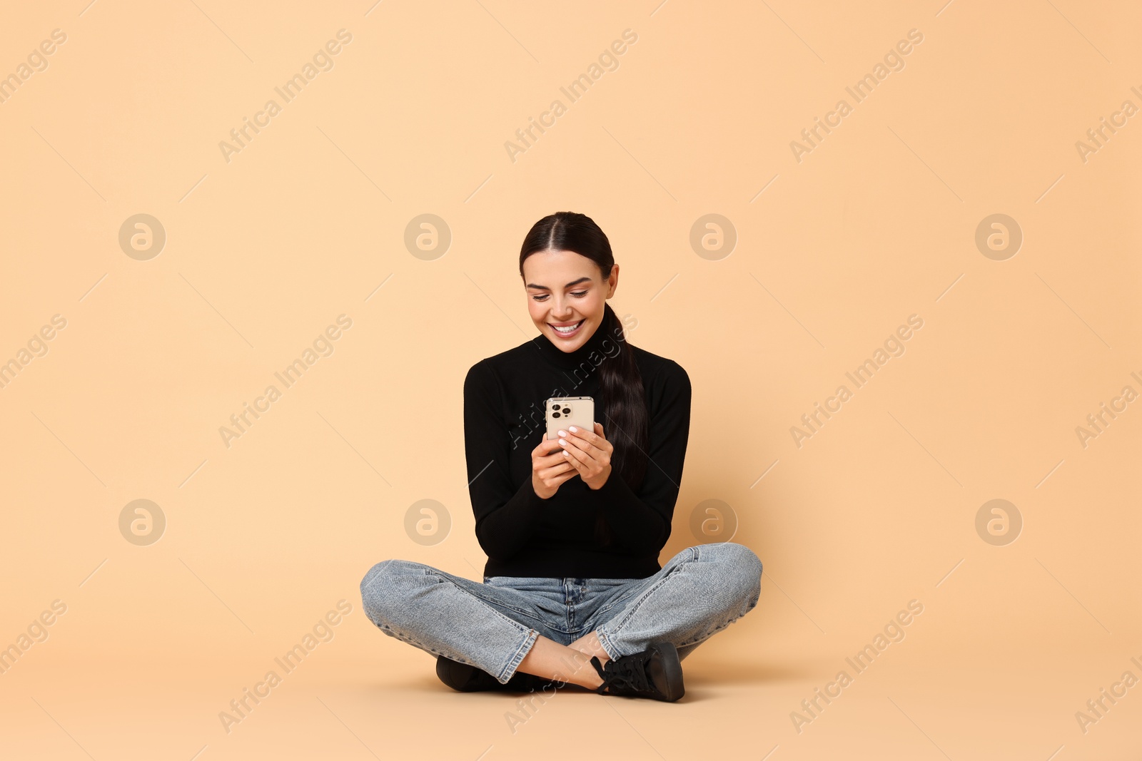 Photo of Smiling woman with smartphone on beige background