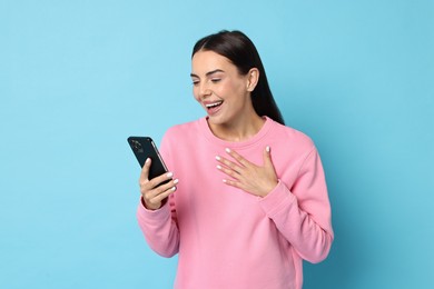 Photo of Happy woman with smartphone on light blue background