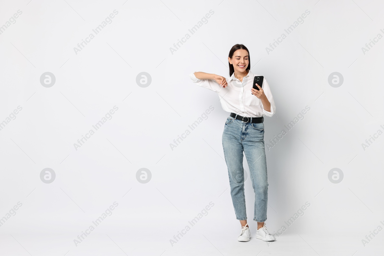 Photo of Smiling woman with smartphone on white background. Space for text