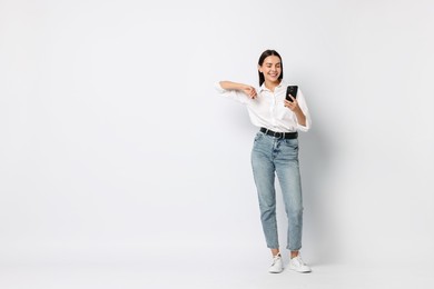 Smiling woman with smartphone on white background. Space for text