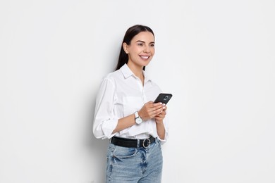 Smiling woman with smartphone on white background