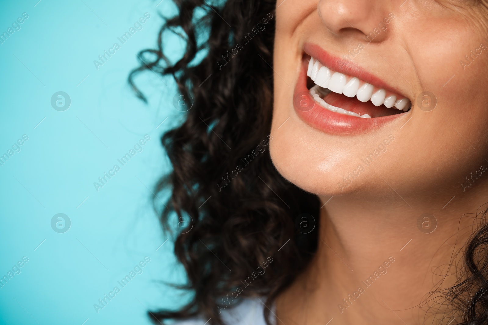 Photo of Smiling woman on light blue background, closeup. Dental veneers