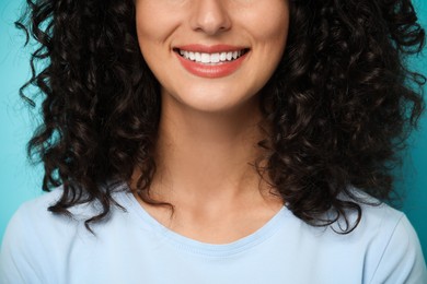 Photo of Smiling woman on light blue background, closeup. Dental veneers