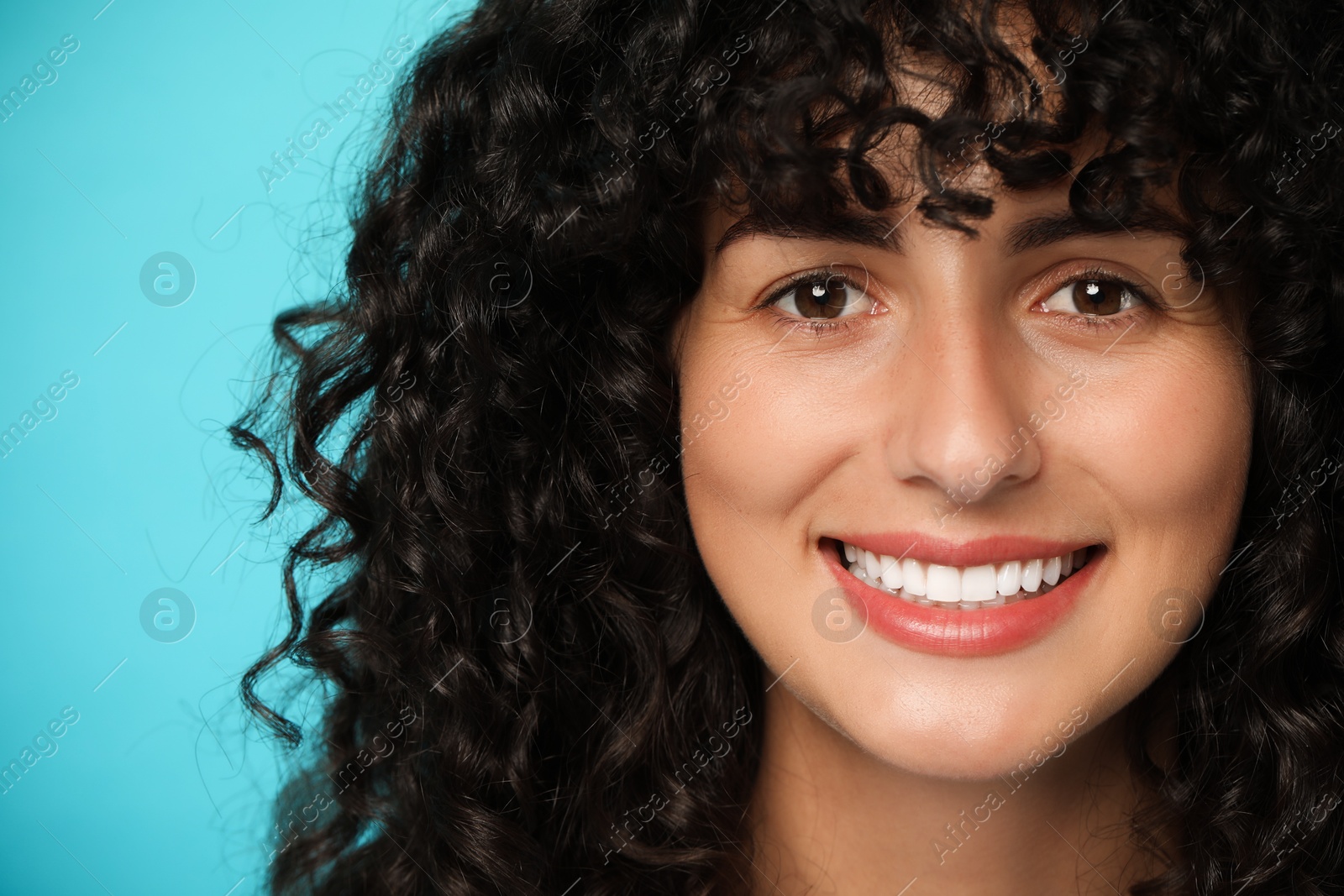 Photo of Happy young woman on light blue background. Dental veneers