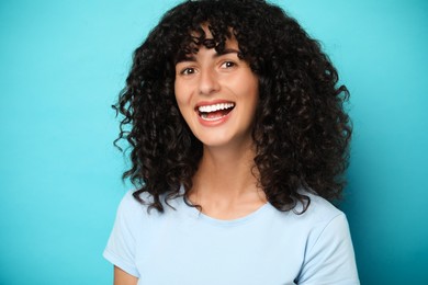 Photo of Happy young woman on light blue background. Dental veneers