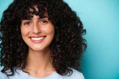 Photo of Happy young woman on light blue background. Dental veneers